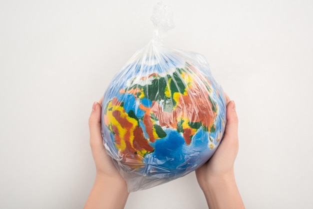 Vista ritagliata della donna che tiene il sacchetto di plastica con il globo sul concetto di riscaldamento globale bianco