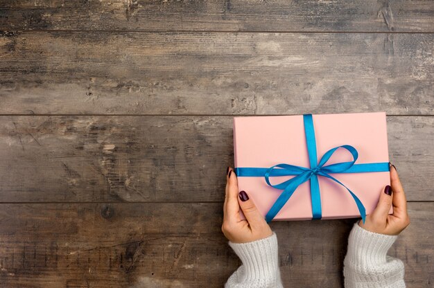 Vista ritagliata della donna che tiene un regalo di natale avvolto con fiocco blu Mani femminili che tengono regalo