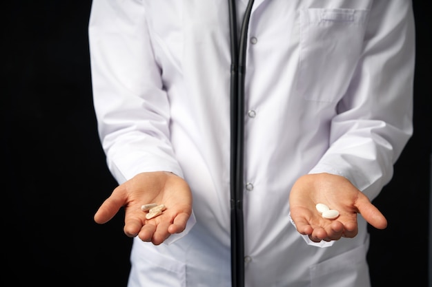 Vista ritagliata della dottoressa tenendo in mano Pillole da scegliere. Scelta difficile tra farmaci. Concetto di farmaci placebo. Concetto di assistenza sanitaria.