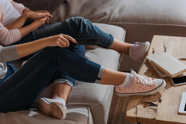 Vista ritagliata della madre che tiene il telecomando vicino al bambino sul divano di casa