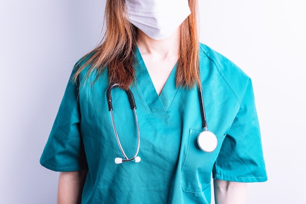 Vista selettiva di una dottoressa di uno stetoscopio appeso al collo di una dottoressa con maschera facciale bianca