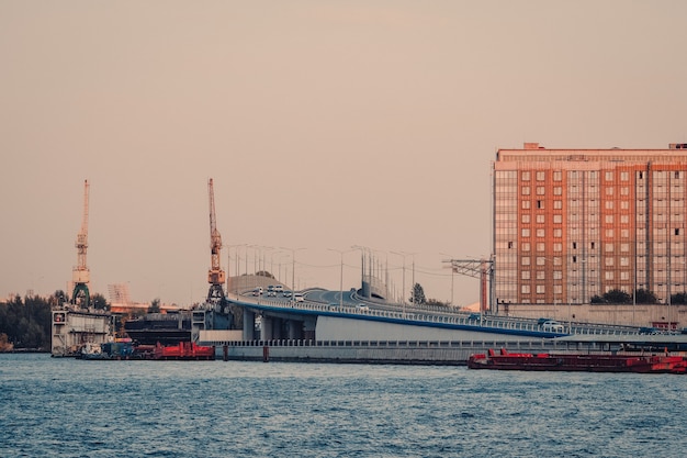 Vista serale di San Pietroburgo con traffico attraverso il viadotto. Cantieri navali di un'impresa industriale società di costruzioni navali Almaz. Russia.