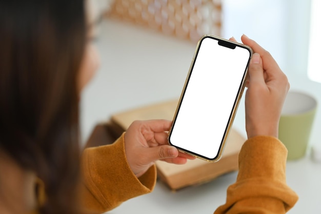 Vista sopra la spalla donna con lo schermo vuoto del telefono cellulare seduta alla scrivania di lavoro