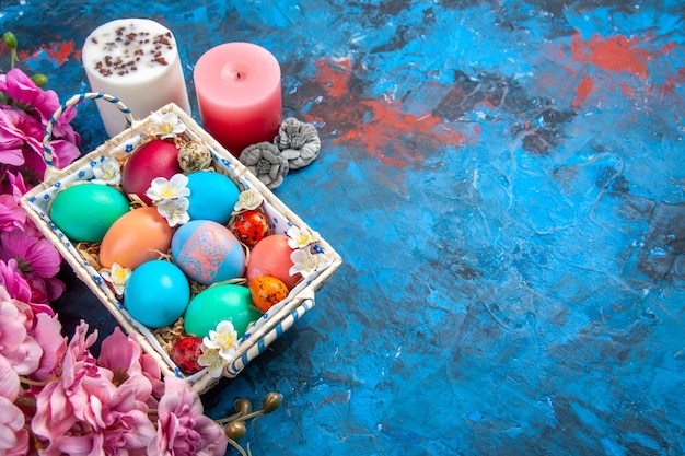 vista sopra le uova di Pasqua colorate all'interno di una scatola carina su superficie blu