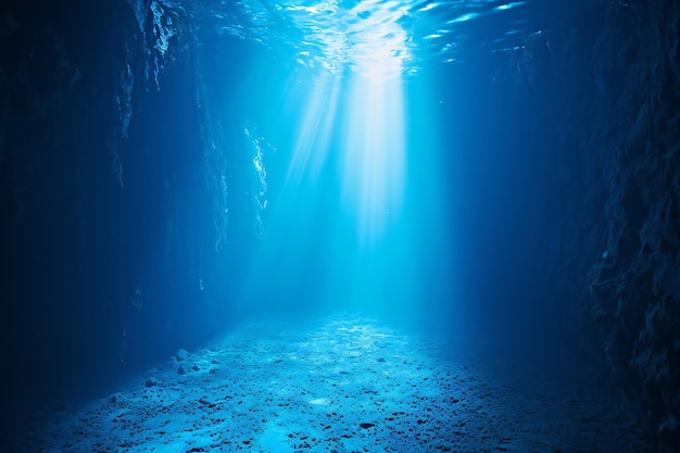 Vista sottomarina di una grotta blu scuro con raggi di luce che attraversano