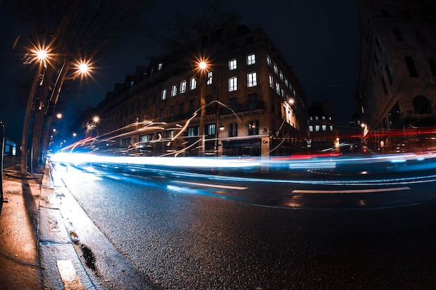 Vista stradale vuota con percorso luminoso a lunga esposizione da una strada di Parigi per lo sfondo del design durante la notte