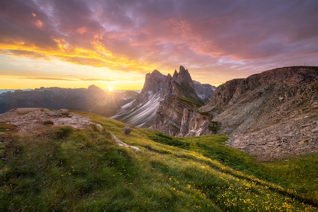 Vista stupefacente dei paesaggi della montagna verde con il cielo dell'oro sulla mattina di alba dalle dolomia, Italia.