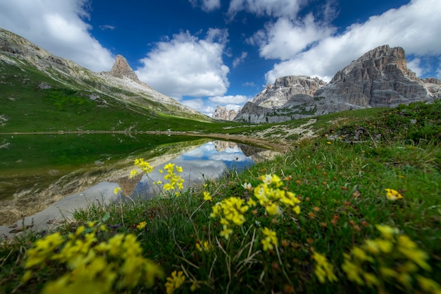 Vista stupefacente dei paesaggi dello stagno e della montagna verde con cielo blu su estate dalle dolomia, Italia.