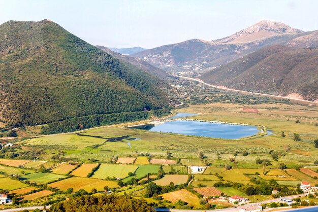 Vista su case, lago artificiale e montagne verdi