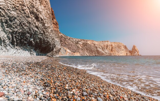 Vista sul mare al tramonto e sulla spiaggia la roccia vulcanica è illuminata dalla calda sabbia e ciottoli del tramonto