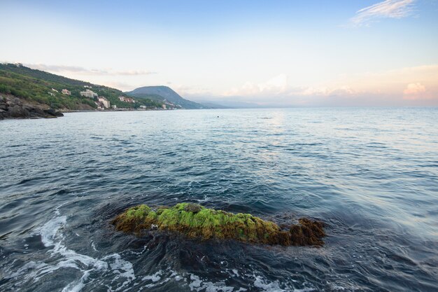 Vista sul mare con montagne e costa rocciosa. Onde blu spumeggianti. Crimea, Russia.