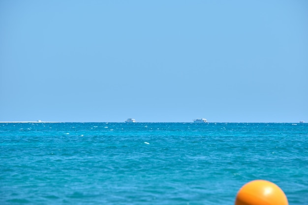 Vista sul mare con superficie increspata dell'acqua di mare blu con navi lontane che galleggiano su onde calme.
