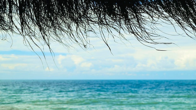 Vista sul mare sotto il tetto di paglia sullo sfondo del concetto di vacanza in spiaggia