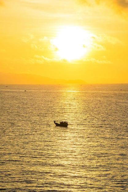 Vista sul mare tropicale con una barca sulla spiaggia sabbiosa all'alba o al tramonto nuvoloso Splendida spiaggia tropicale al tramonto con piccola barca e cielo rosa per viaggi e vacanze in vacanza tempo di relax Città di Vung tau