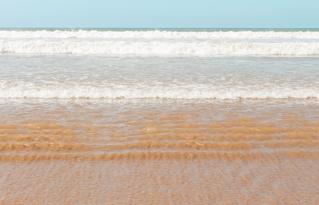 Vista sulla spiaggia sabbiosa dell'oceano Atlantico con le onde che arrivano in linee parallele in una luminosa giornata di sole