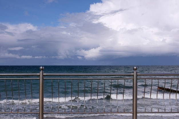 Vista sulle onde del mare sotto il cielo blu con nuvole dense sullo skyline dall'argine su da nuvoloso ventoso