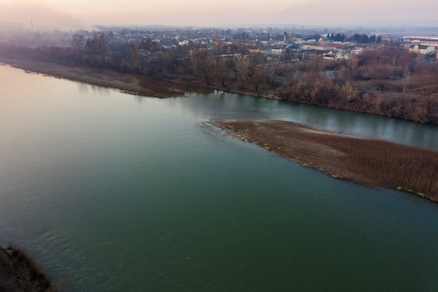 Vista superiore aerea, panorama della campagna dell'acqua di fiume calma e isola con erba asciutta, orizzonte nebbioso sotto cielo blu il giorno soleggiato. Fotografia di droni.