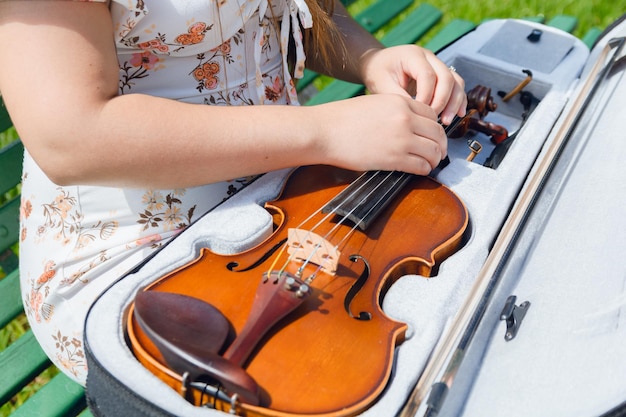 vista superiore artista femminile irriconoscibile per strada che apre la cerniera del violino dalla custodia per tirarlo fuori