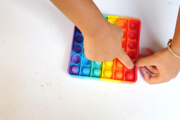 vista superiore bambini che premono pop it arcobaleno colore brillante con le dita isolare su uno sfondo biancoanti stress sensoriale pop it giocattoli