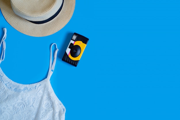 Vista superiore degli accessori e del vestito della spiaggia del fondo di vacanza estiva su fondo blu.