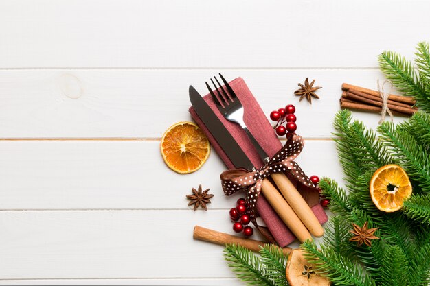 Vista superiore degli utensili sul tovagliolo festivo su fondo di legno. Decorazioni natalizie con frutta secca e cannella. Cena di Capodanno con copyspace