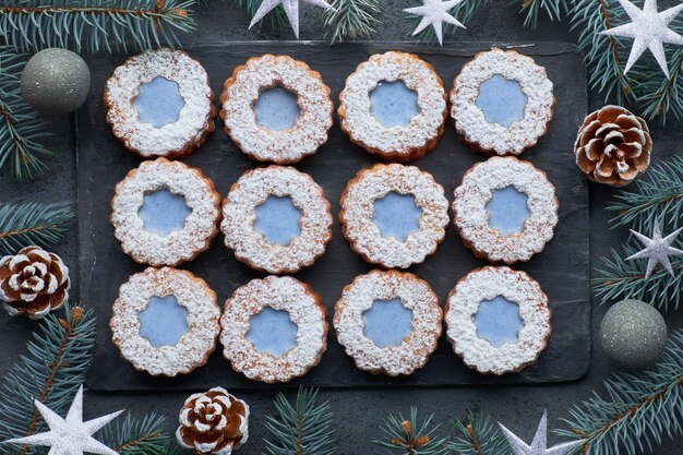 Vista superiore dei biscotti di Linzer del fiore con vetri blu sulla parete scura di inverno