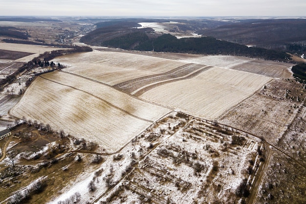 Vista superiore dei campi nevosi vuoti e colline boscose sul cielo nuvoloso