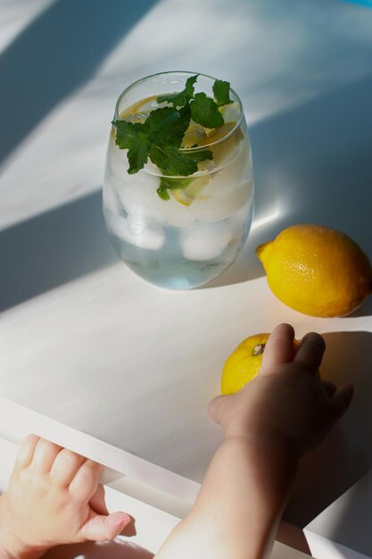 vista superiore del bicchiere d'acqua con menta, limone e ghiaccio sul tavolo bianco, copia spazio