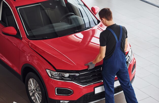 Vista superiore del lavoratore maschio in uniforme che ripara l'automobile rossa