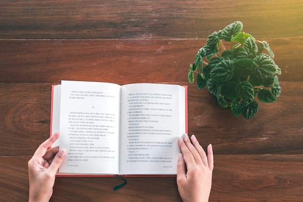 Vista superiore del libro di lettura della bella donna della ragazza sulla tavola di legno