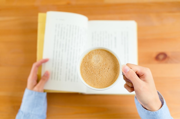 Vista superiore del libro di lettura della donna e della bevanda del caffè