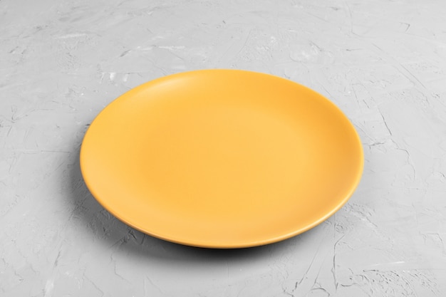 Vista superiore del piatto giallo vuoto rotondo opaco su cemento grigio