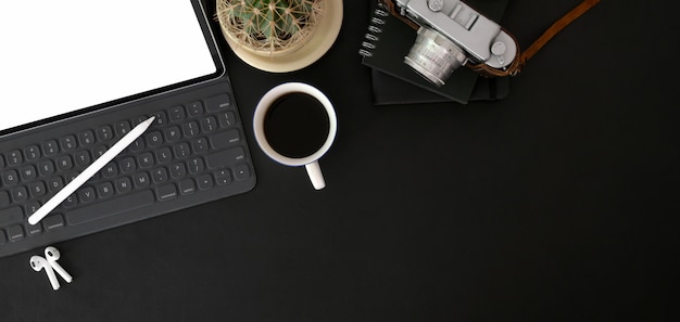 Vista superiore del posto di lavoro alla moda fotografo con mock up tavoletta digitale, fotocamera e articoli per ufficio sul tavolo nero