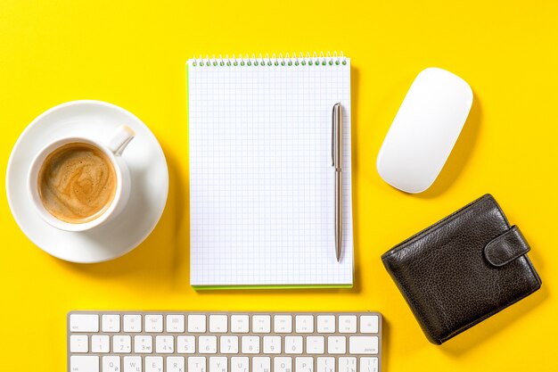 Vista superiore del posto di lavoro di affari con la tazza di caffè, area di lavoro vuota sulla tavola gialla.