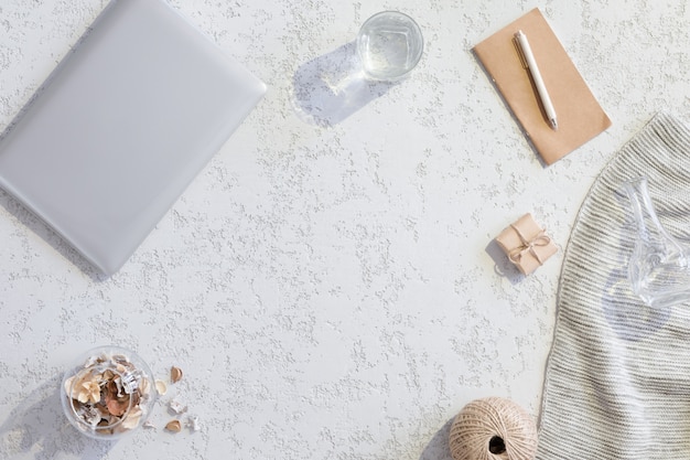 Vista superiore dell'area di lavoro o della scrivania con il computer portatile, biscotti allo zenzero, cono su fondo bianco strutturato con luce dura