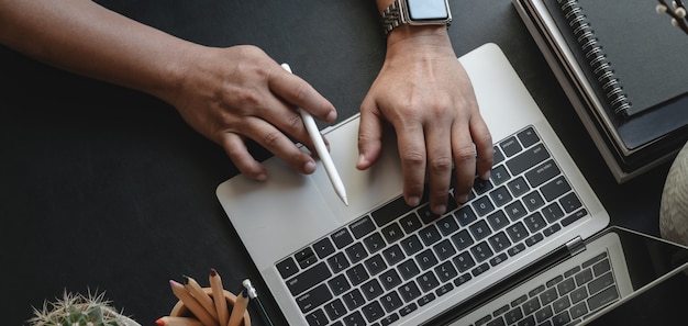 Vista superiore dell'uomo d'affari che scrive sul computer portatile mentre lavorando al suo progetto