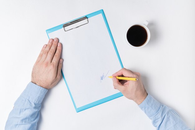 Vista superiore della carta delle mani e della tazza di caffè maschii. L'uomo mette la firma sulla carta