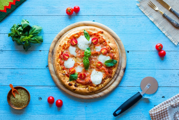 Vista superiore della classica pizza italiana margherita su un tavolo di legno con condimenti