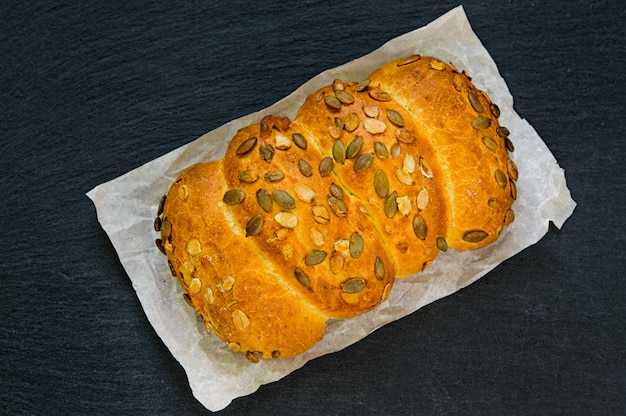 Vista superiore della pagnotta di pane con semi di zucca sul bordo di pietra ardesia nera