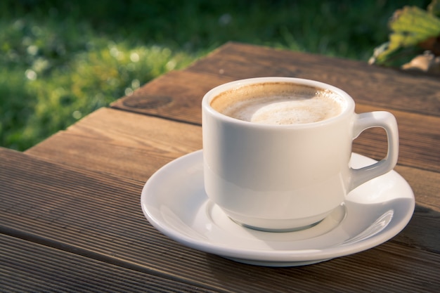 Vista superiore della tazza di caffè sul fondo di legno della tavola. Bella mattinata, outdiir, luce del sole primaverile.