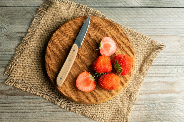 Vista superiore delle fragole organiche rresh con il coltello sul tagliere di legno. Stile rustico.