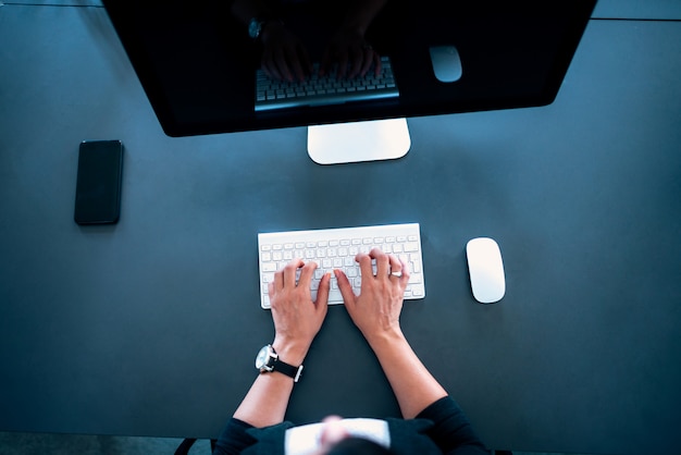 Vista superiore delle mani femminili digitando sulla tastiera wireless.