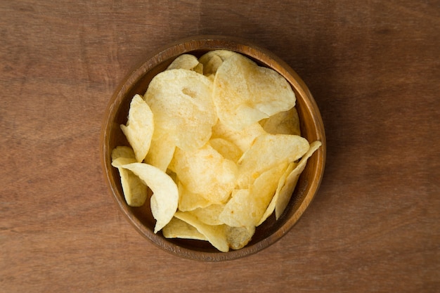 Vista superiore delle patatine fritte in ciotola di legno su fondo di legno.