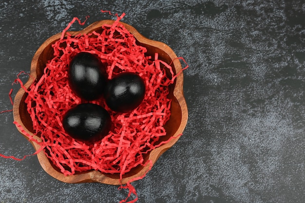 Vista superiore delle uova di Pasqua nere in piatto di legno.