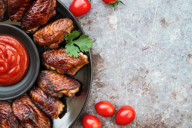 Vista superiore di ali di pollo arrosto in lamiera con salsa di pomodoro su sfondo grunge