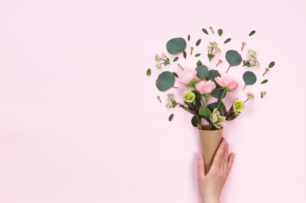 Vista superiore di composizione floreale di bello fiore della rosa di rosa nella cornetta di Kraft su fondo bianco, disposizione piana, copyspace