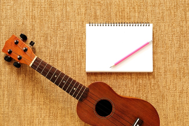 Vista superiore di ukulele con notebook e matita