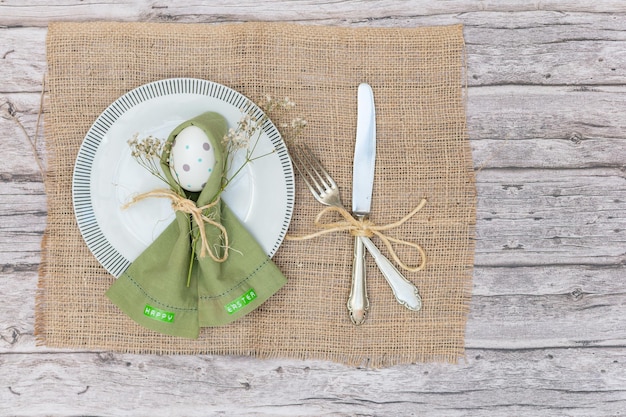 Vista superiore di un piatto con un tovagliolo dipinto di argento per le uova di Pasqua e testo di Buona Pasqua