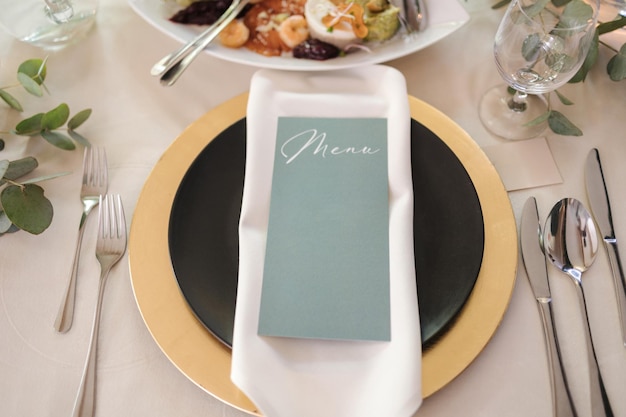Vista superiore di un tavolo bellissimo e servito in un ristorante con piatto d'oro e un sacco di posate