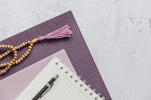 Vista superiore di una stuoia viola di yoga, cattive perle di legno su fondo bianco. Accessori essenziali per praticare yoga e meditazione. Copia spazio